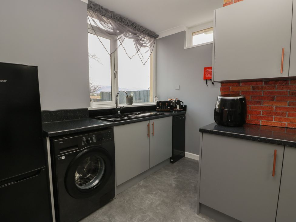 A kitchen with appliances and cabinet storage at Shotts Cottage in Stirling