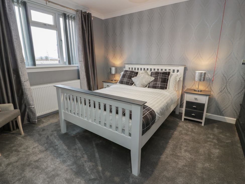 A bedroom with a bed and nightstand at Shotts Cottage in Stirling