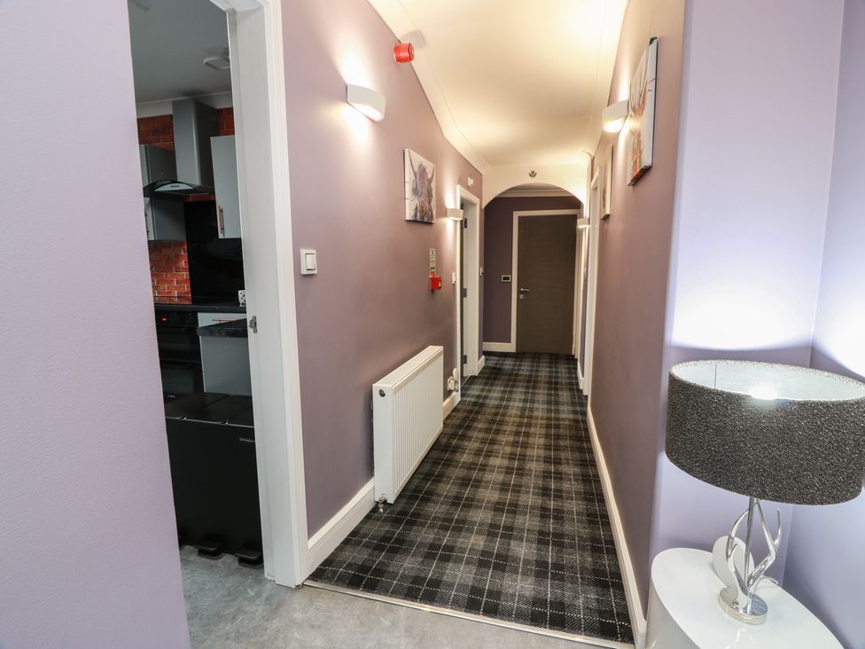 A hallway with a lamp and kitchen access at Shotts Cottage in Stirling
