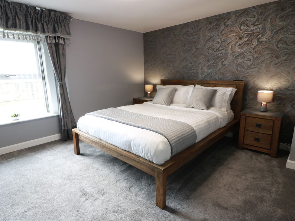 A bedroom with a bed and nightstands at Shotts Cottage in Stirling