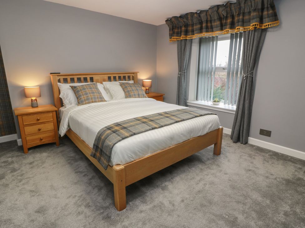 A bedroom with a bed and nightstands at Shotts Cottage in Stirling