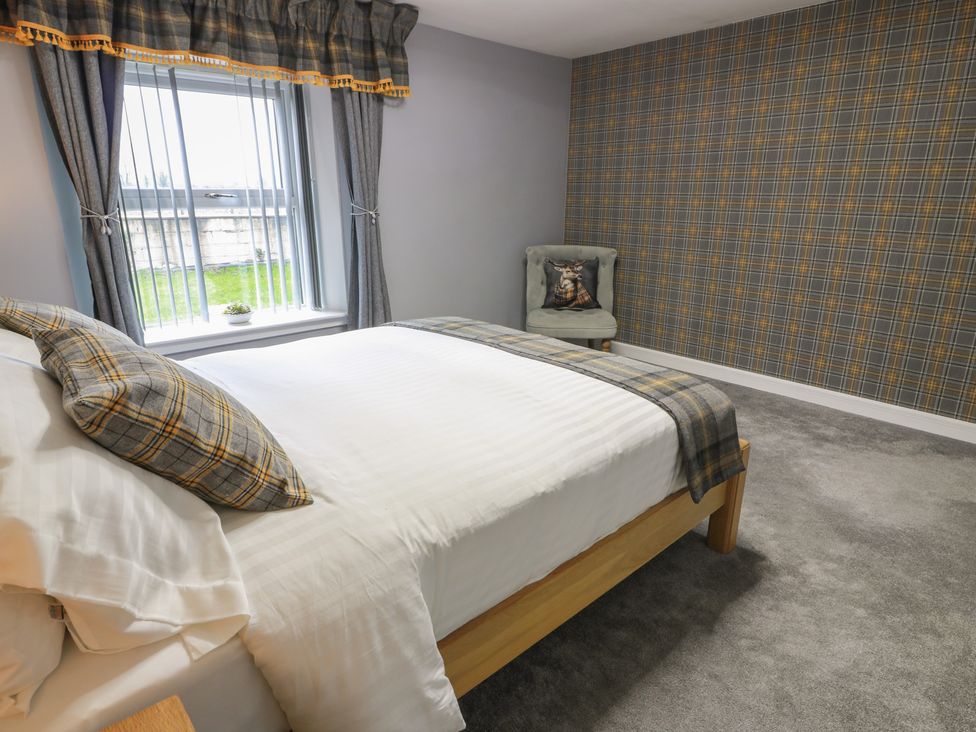 A bedroom with a bed and patterned wallpaper at Shotts Cottage in Stirling