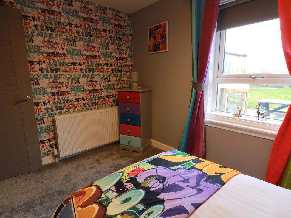 A bedroom with a bed and colorful drawer at Shotts Cottage in Stirling