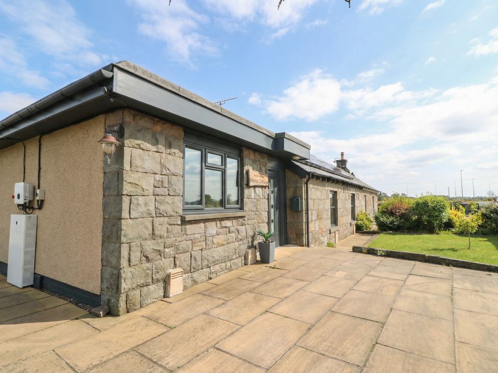 A cottage exterior with a stone wall and garden at Shotts Cottage in Stirling