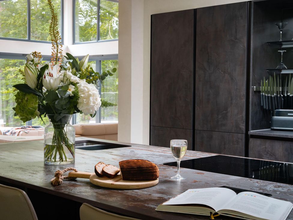A kitchen with a cutting board, glass of wine, and flowers at Heilan Roo in Killiecrankie near Pitlochry and Blair Atholl