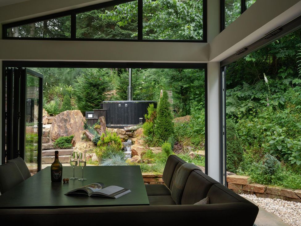 A dining room with a view of a garden and hot tub at Heilan Roo in Killiecrankie near Pitlochry and Blair Atholl