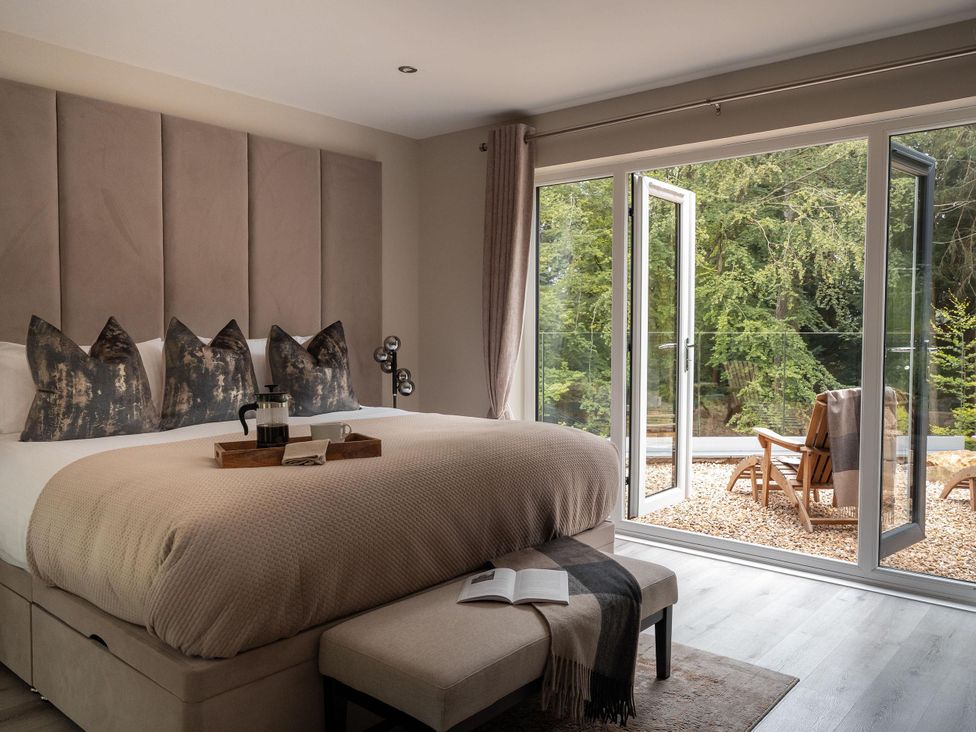 A bedroom with a bed and sliding glass door at Heilan Roo Killiecrankie near Pitlochry and Blair Atholl