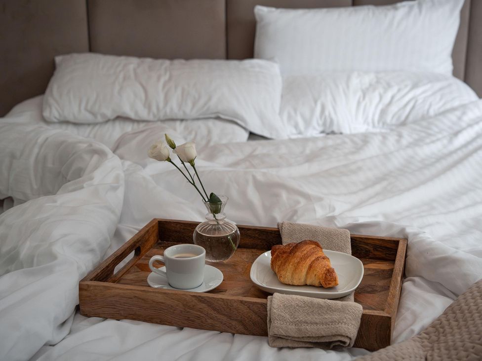A tray with coffee, a croissant, and flowers on a bed at Heilan Roo in Killiecrankie near Pitlochry and Blair Atholl