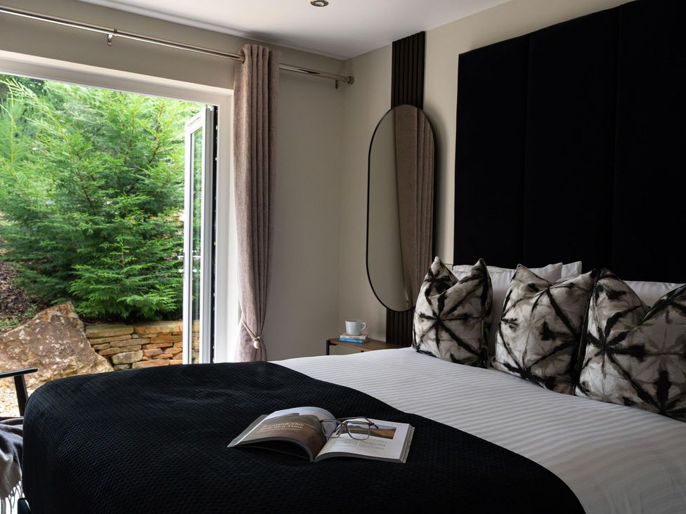 A bedroom with a bed and window overlooking greenery at Heilan Roo in Killiecrankie near Pitlochry and Blair Atholl