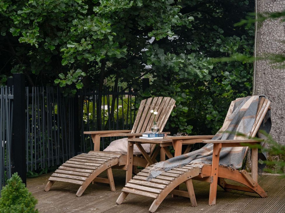 A garden with sunloungers and a table at Heilan Roo Killiecrankie near Pitlochry and Blair Atholl