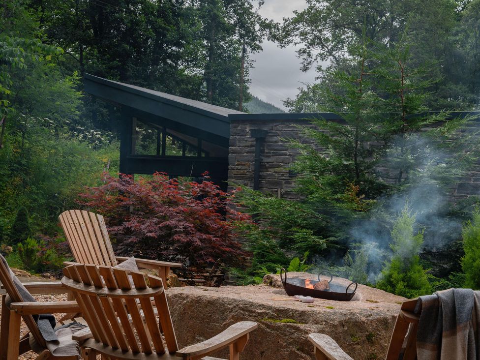 A garden with a fire pit and wooden chairs at Heilan Roo Killiecrankie near Pitlochry and Blair Atholl