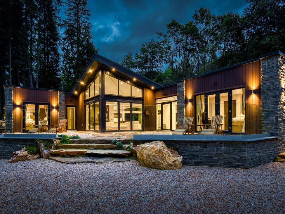 A house exterior with patio chairs and trees at Heilan Roo in Killiecrankie near Pitlochry and Blair Atholl