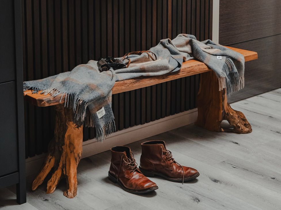 An entryway with a wooden bench a scarf and brown boots at Heilan Roo Killiecrankie near Pitlochry and Blair Atholl