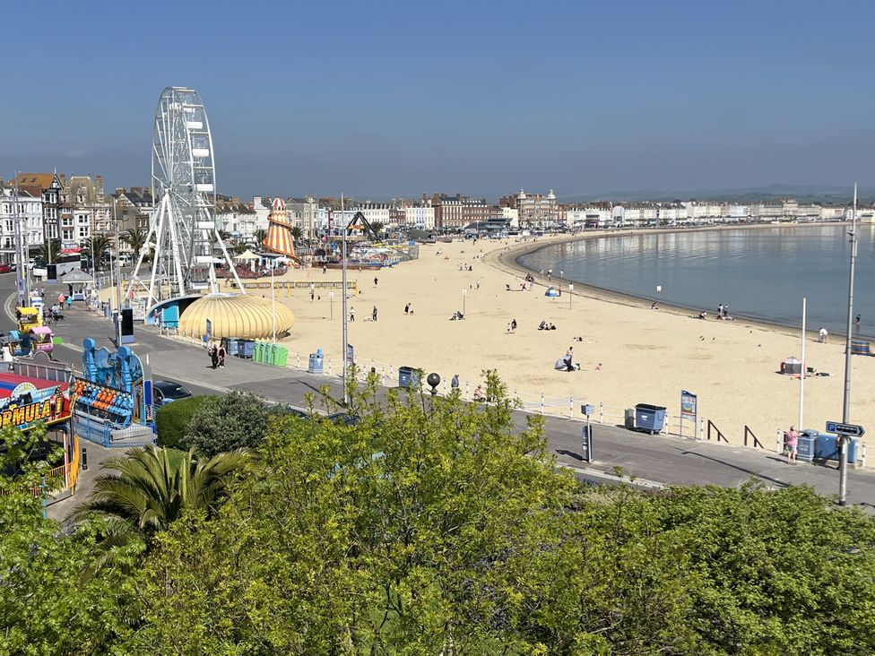 A beach with a ferris wheel and carnival rides at Seasides in Weymouth