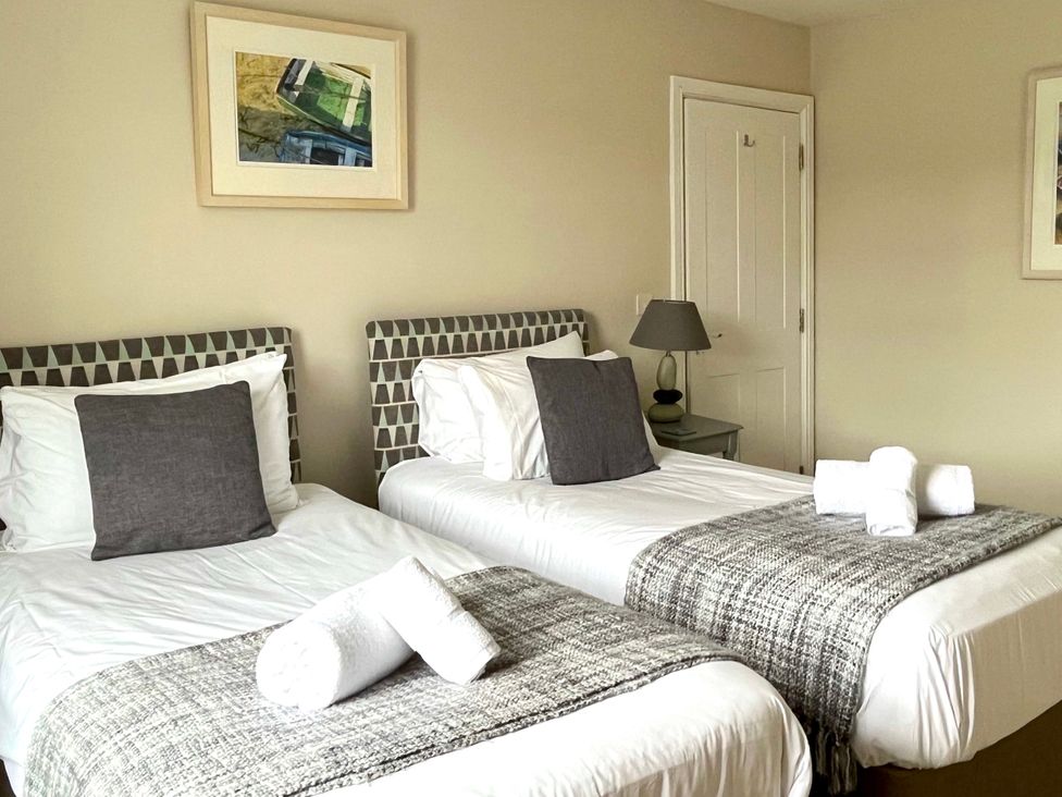 A bedroom with two beds, a lamp, and artwork at Seasides in Weymouth