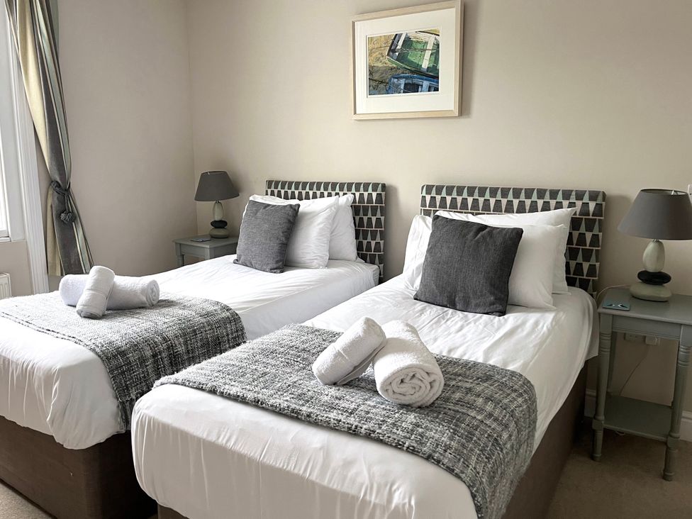 A bedroom with twin beds and a bedside table at Seasides in Weymouth