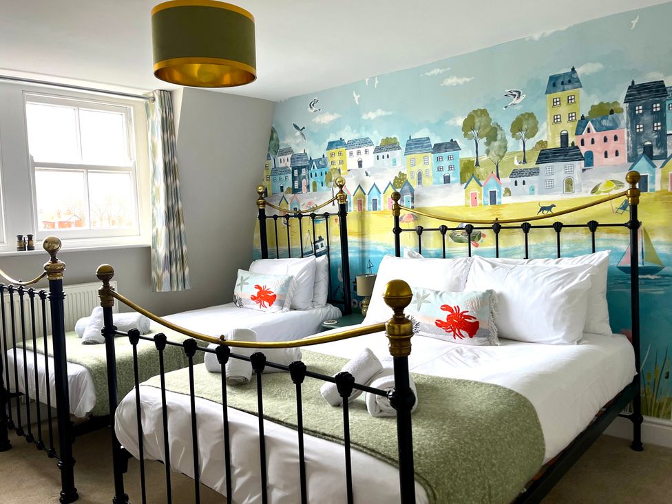 A bedroom with two beds and a mural at Seasides in Weymouth