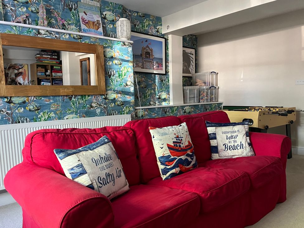 A living room with a red sofa and foosball table at Seasides in Weymouth