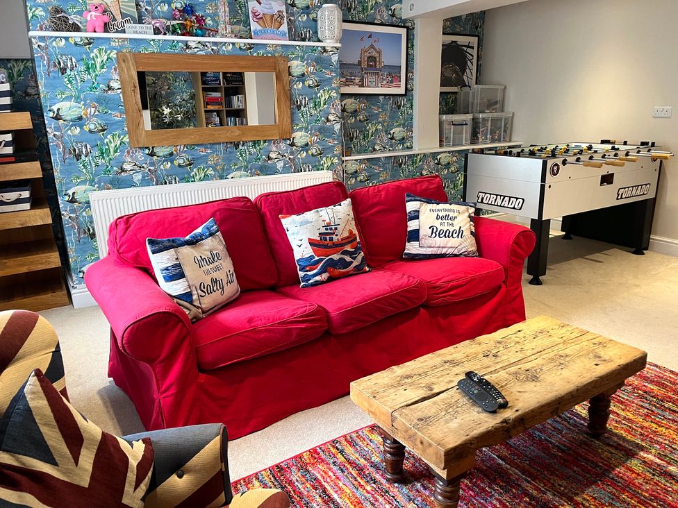 A living room with a red sofa and foosball table at Seasides in Weymouth