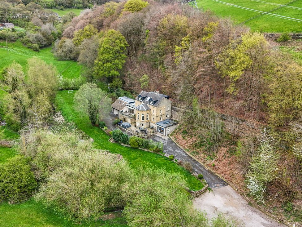 An aerial view of a house surrounded by trees and garden at Belvedere Farm in Hipperholme
