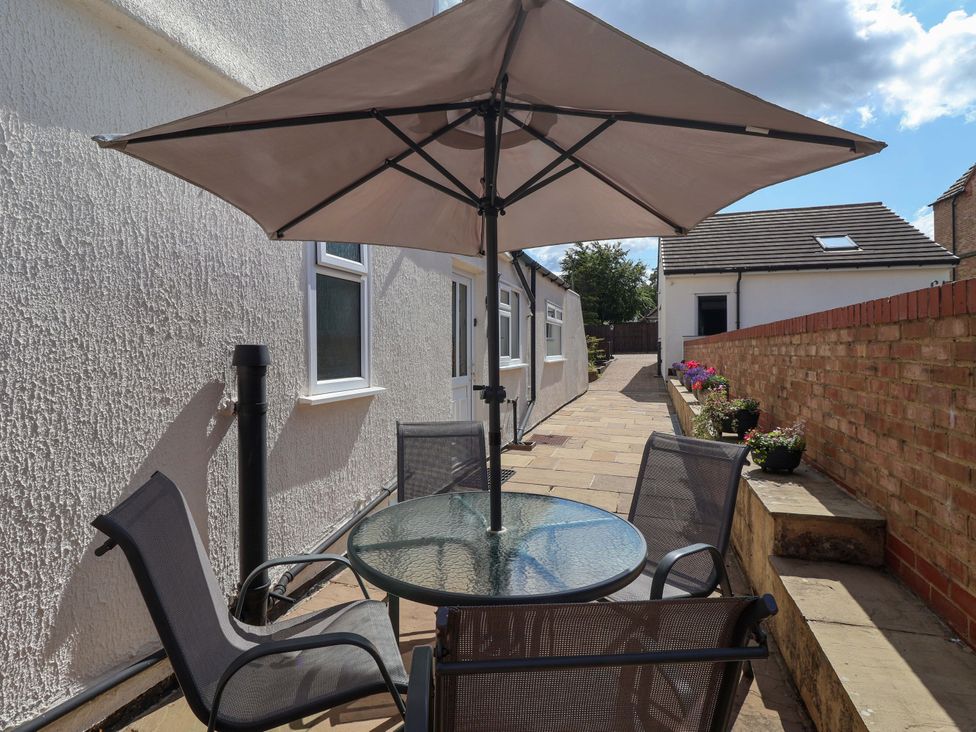 A table with umbrella and chairs in an outdoor area at 3 Springhaven in Hampsthwaite