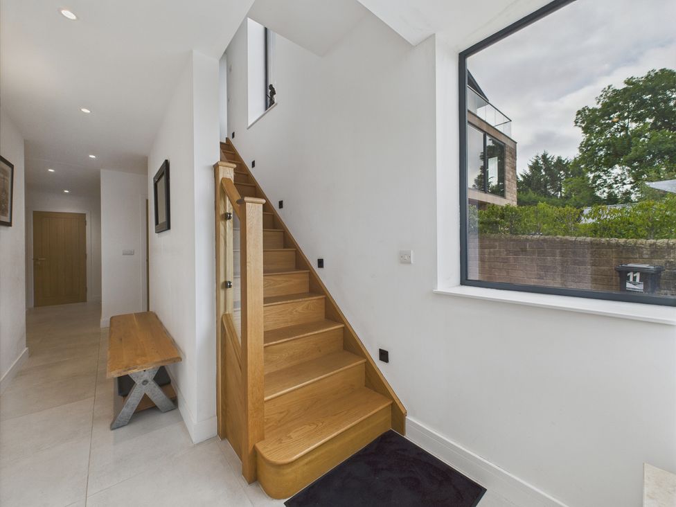 A hallway with a staircase and a bench at Oakwood House Tansley near Matlock