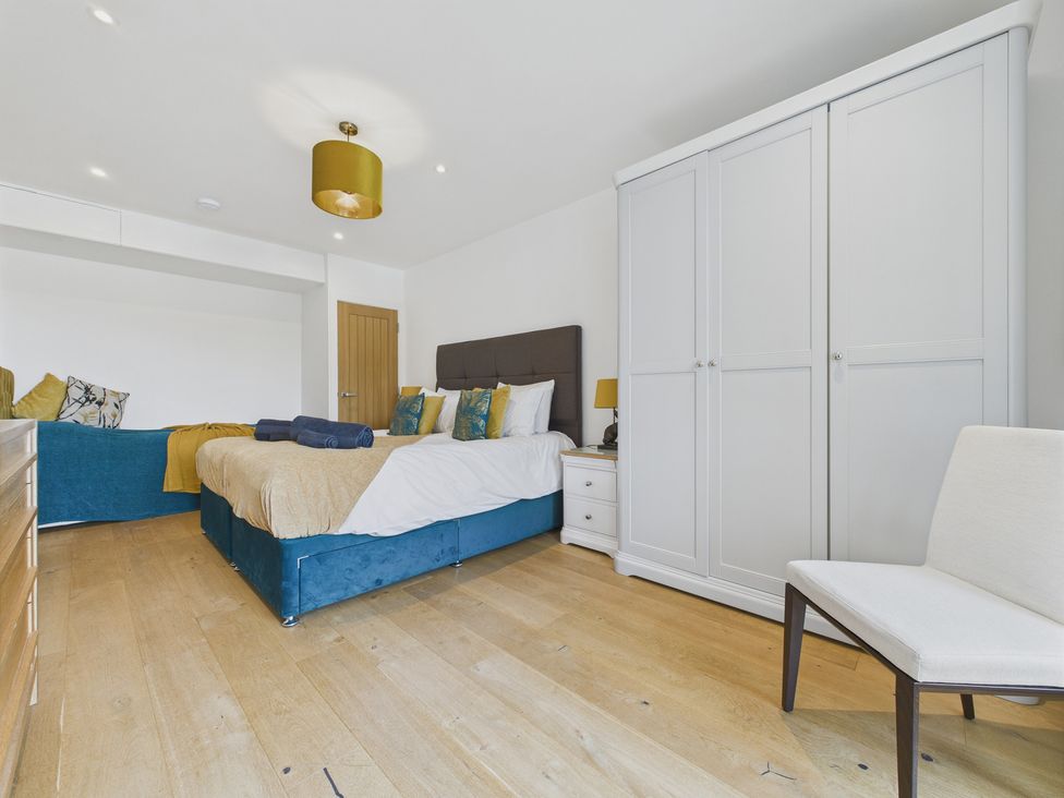A bedroom with a bed, wardrobe, and chair at Oakwood House Tansley near Matlock
