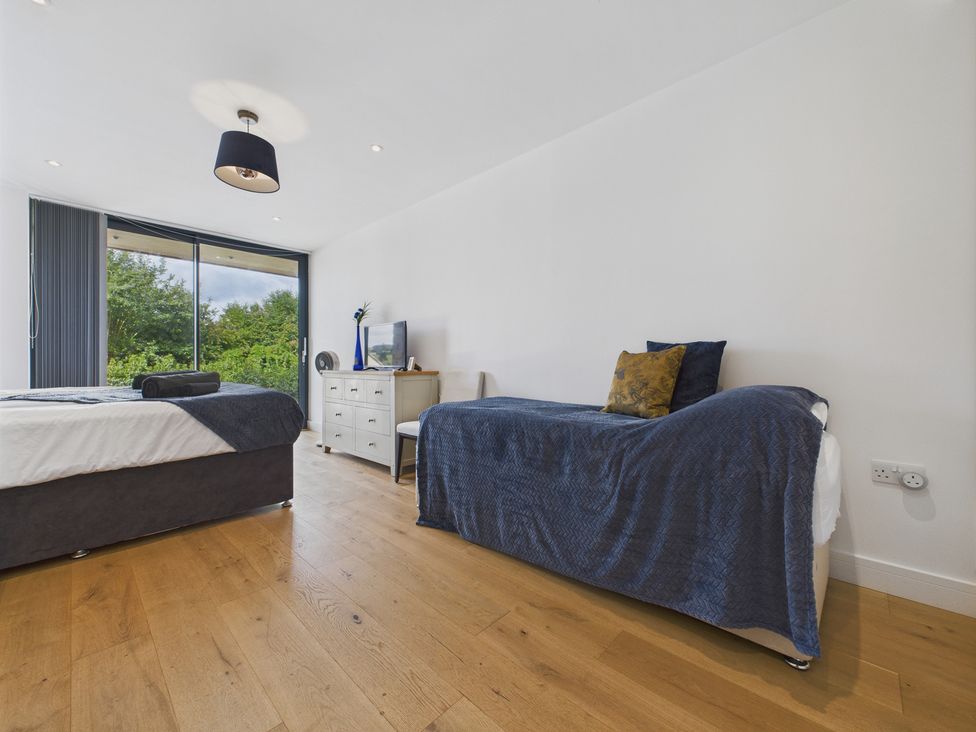 A bedroom with a bed, dresser, chair and television at Oakwood House, Tansley near Matlock