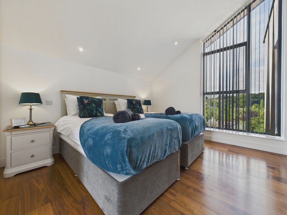 A bedroom with two beds and a large window at Oakwood House Tansley near Matlock