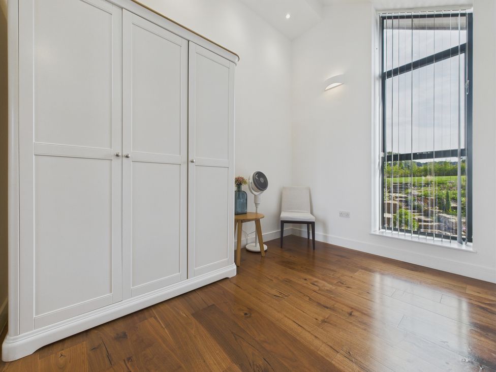A bedroom with a wardrobe and a window at Oakwood House Tansley near Matlock