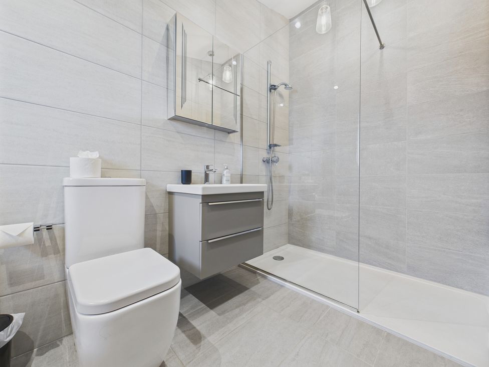 A bathroom with a toilet, sink, shower, and cabinet at Oakwood House in Tansley near Matlock