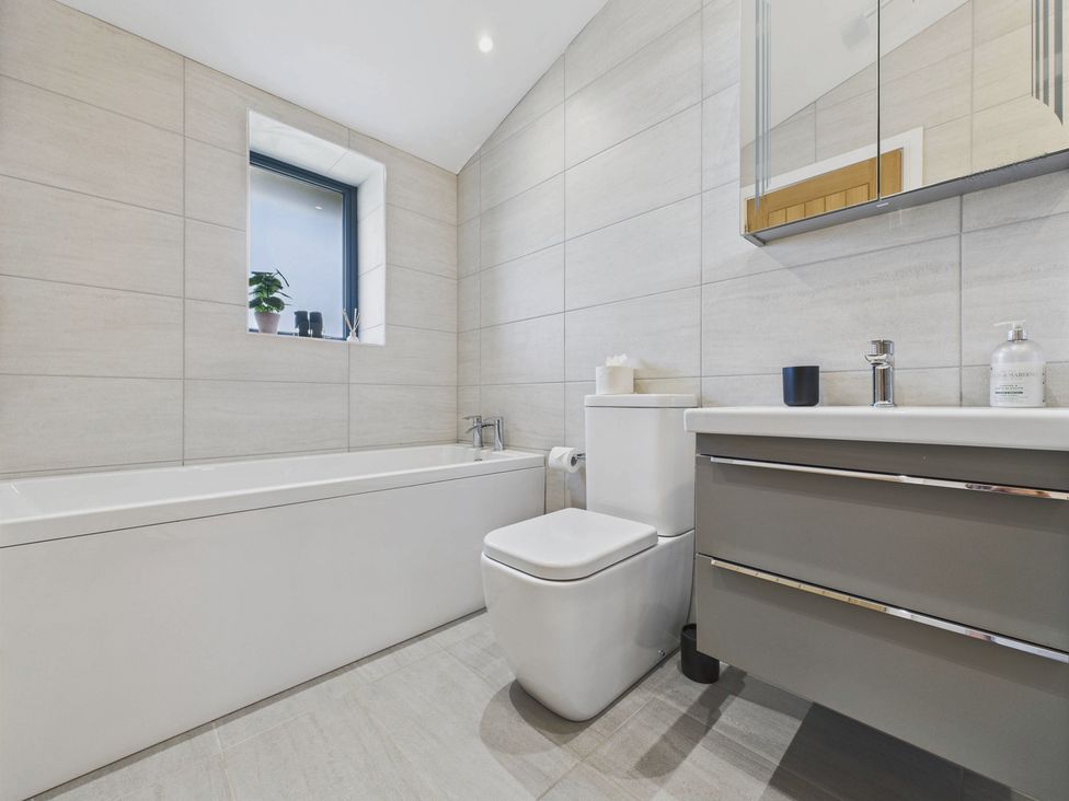 A bathroom with bathtub, toilet, sink and mirror at Oakwood House in Tansley near Matlock
