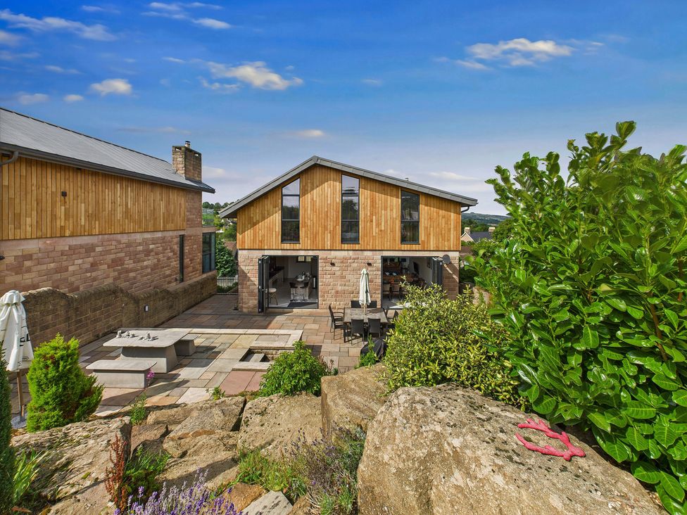 A house with a patio area and outdoor furniture at Oakwood House in Tansley near Matlock