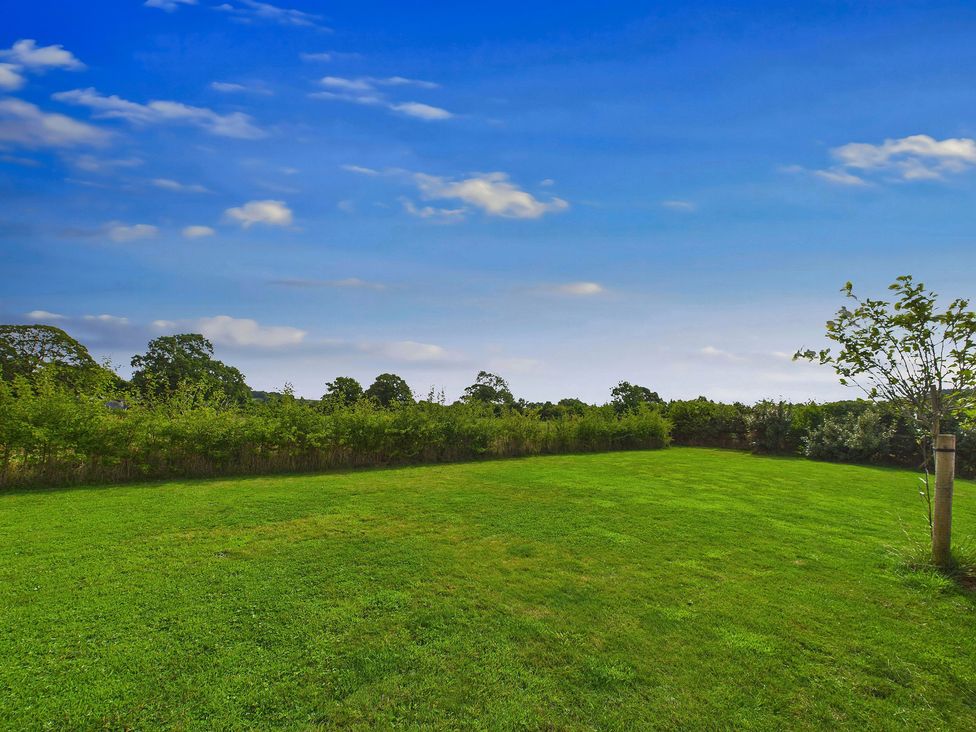 A grassy area with trees and bushes under a blue sky at Oakwood House Tansley near Matlock