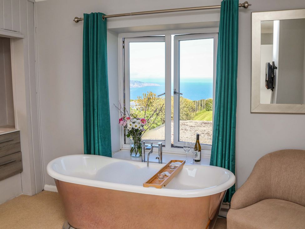 A bathroom with a bathtub and window view at Voebroch in Lythe