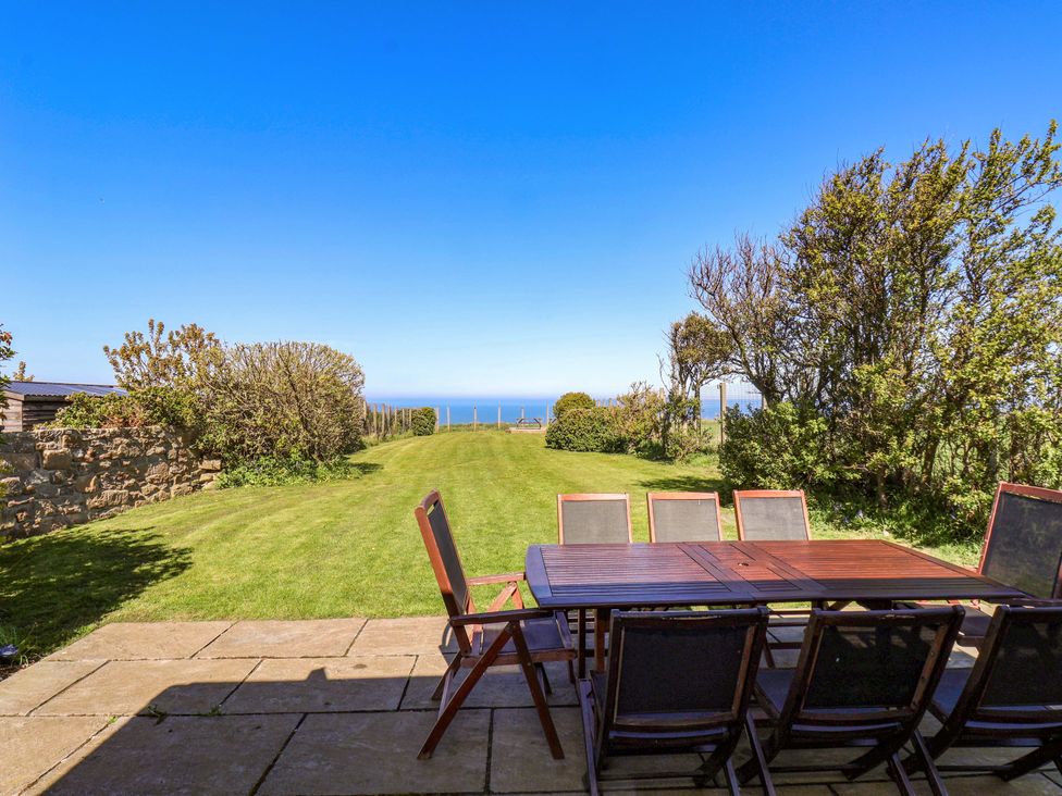 A garden with a table and chairs overlooking the sea at Voebroch in Lythe