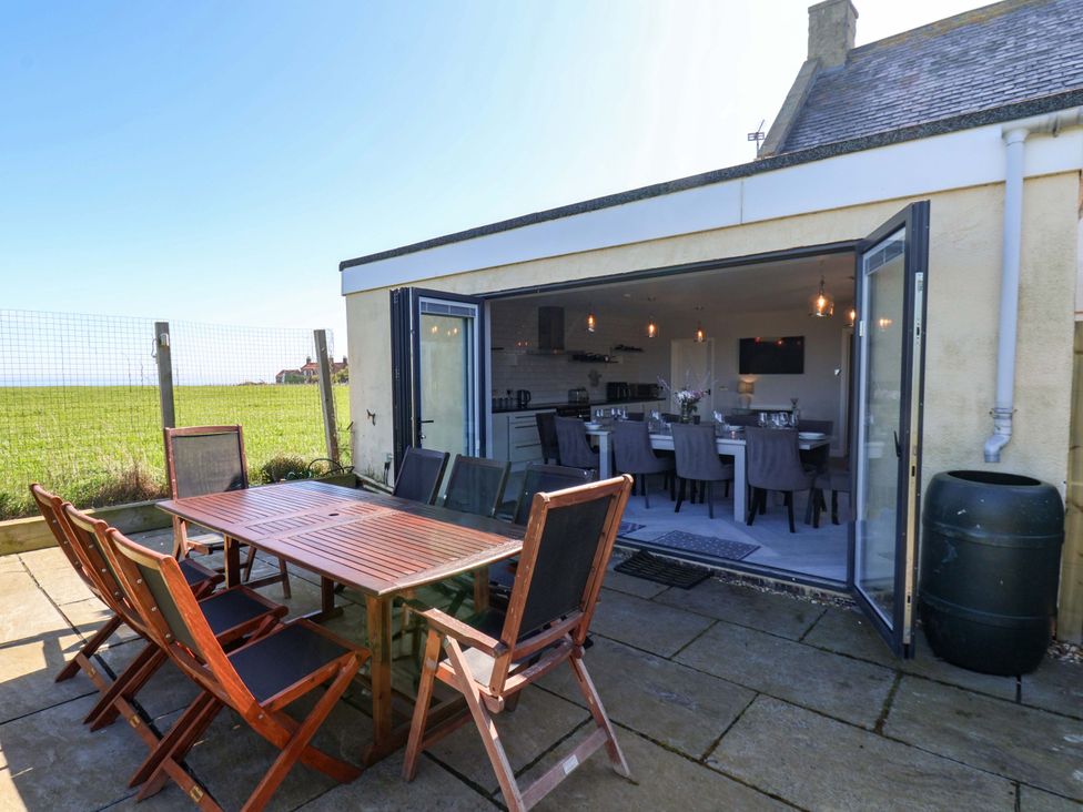 An outdoor dining area with wooden table and chairs at Voebroch in Lythe