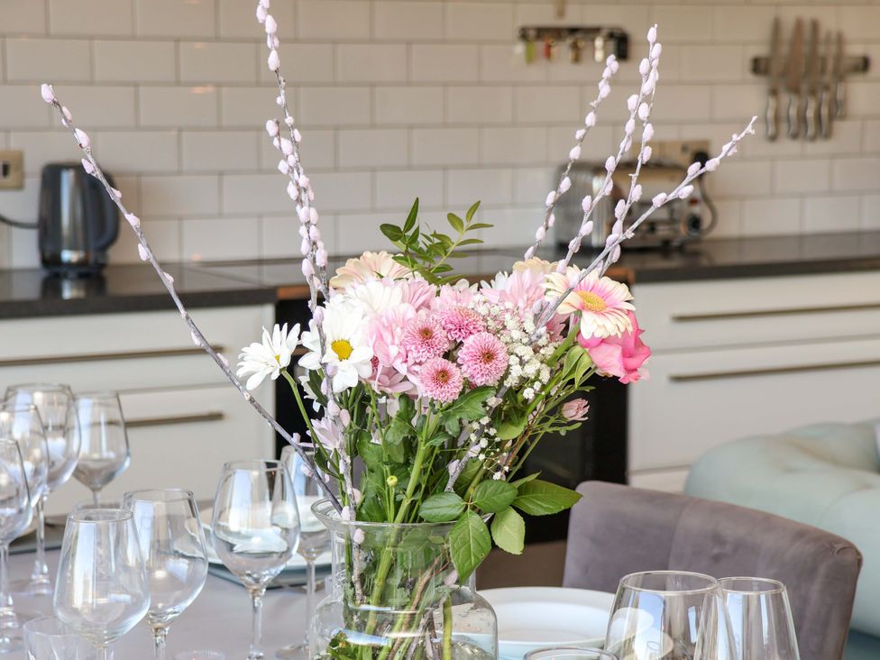A dining room table set with flowers and wine glasses at Voebroch in Lythe