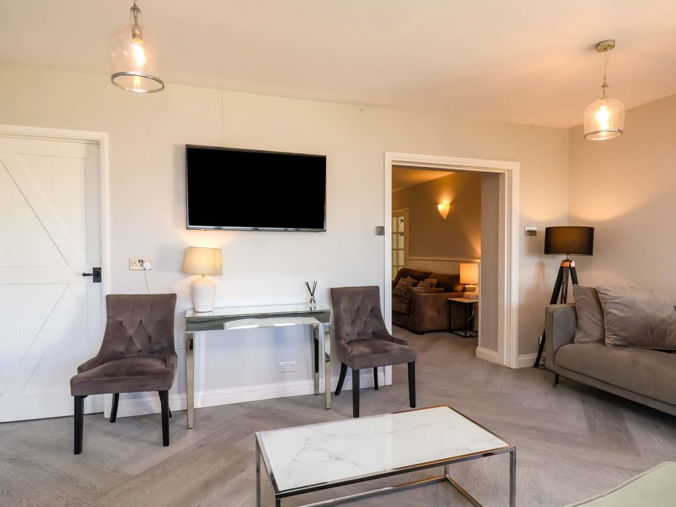 A living room with a television and chairs at Voebroch in Lythe