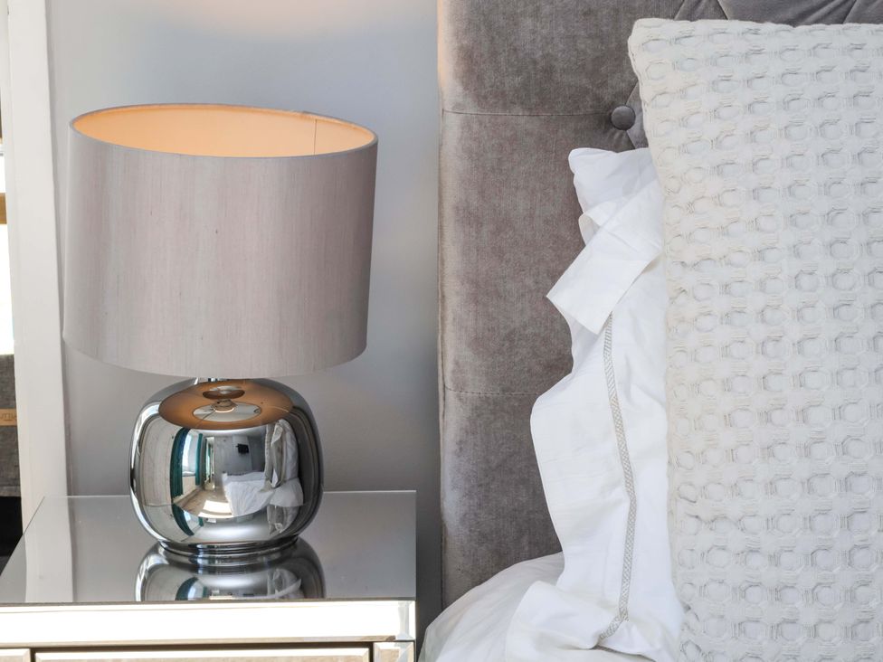 A bedroom with a lamp and pillows on a bedside table at Voebroch in Lythe