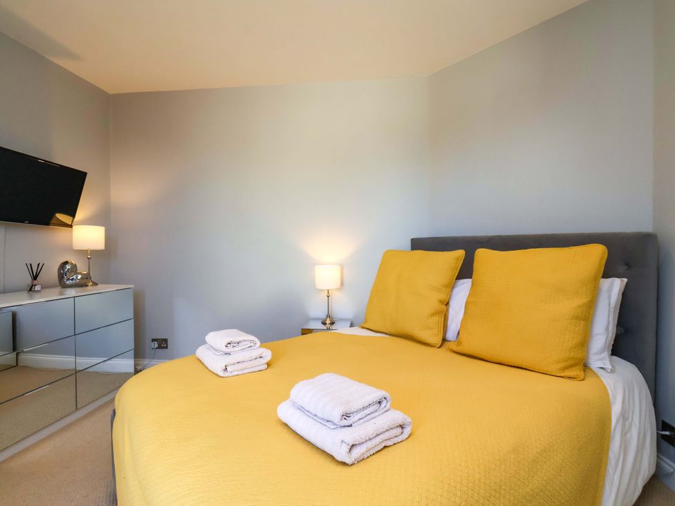 A bedroom with a yellow bedspread and mirrored dresser at Voebroch in Lythe