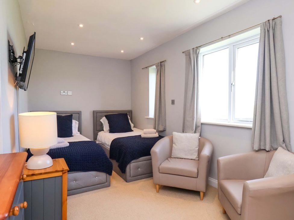 A bedroom with two beds and an armchair at Voebroch in Lythe