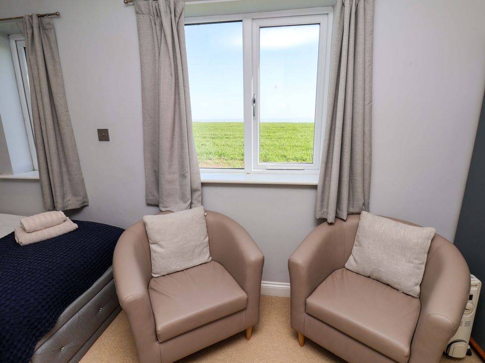 A bedroom with two armchairs and a window at Voebroch in Lythe