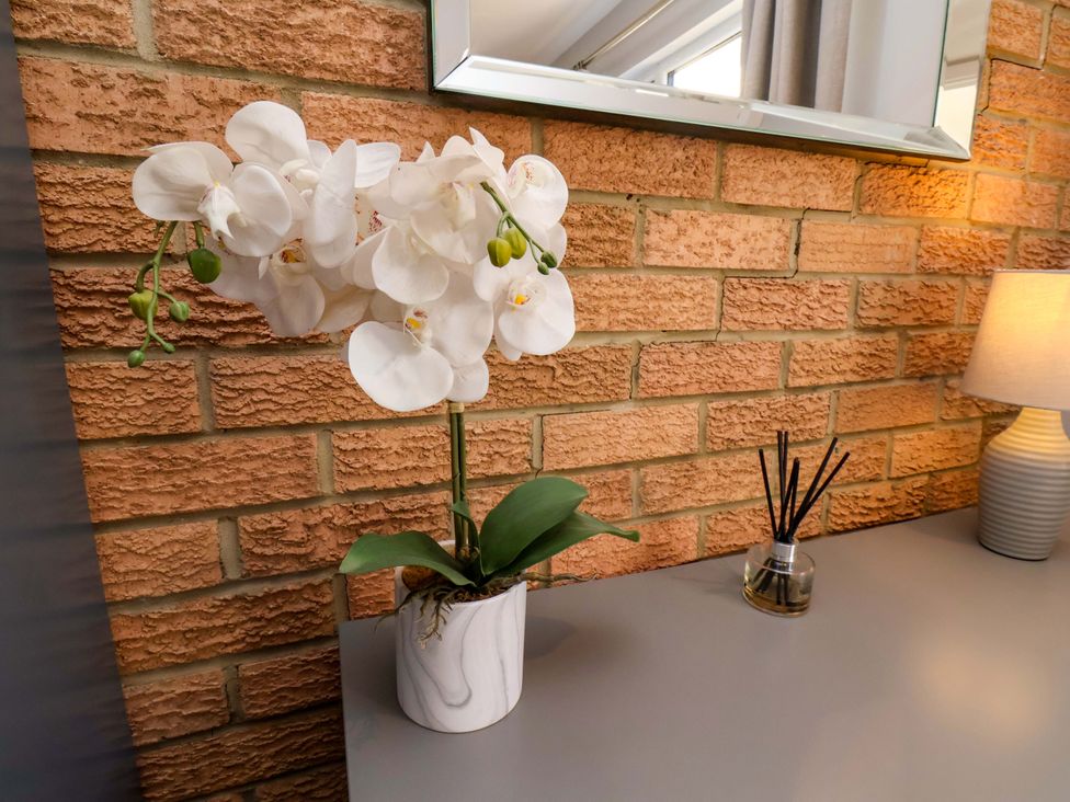 A table with a flower, a mirror, and a lamp at Voebroch in Lythe