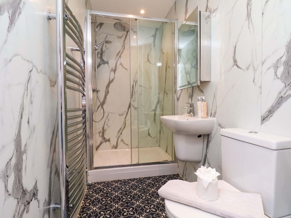 A bathroom with a shower, sink, toilet and towel rack at Voebroch in Lythe