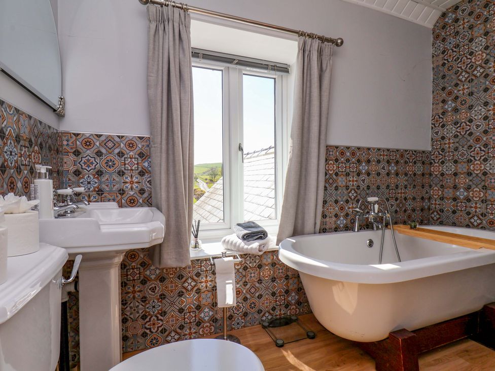 A bathroom featuring a bath tub and sink with decorative tiles at Voebroch in Lythe