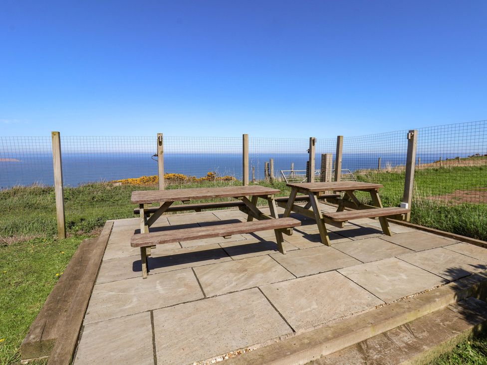 An outdoor seating area with tables and a view of the sea at Voebroch in Lythe