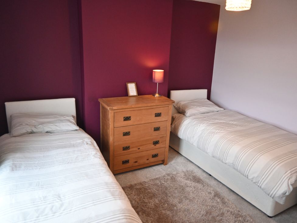A bedroom with two single beds separated by a wooden chest of drawers with a lamp on top at Overchurch in Hythe
