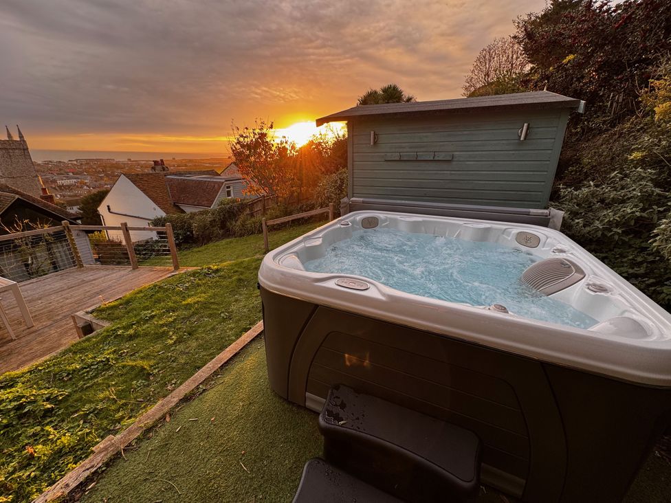 A hot tub in a garden with a sunset at Overchurch in Hythe