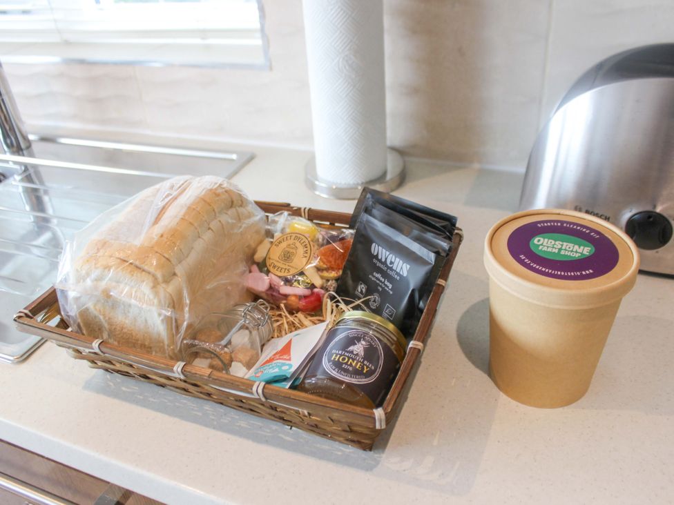 A kitchen with a basket of bread and sweets next to a container and coffee at Simples Dartmouth